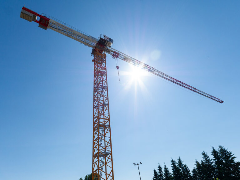 Zdjęcie przedstawiające wysoki żuraw, z perspektywy żabiej, pod ostre słońce.